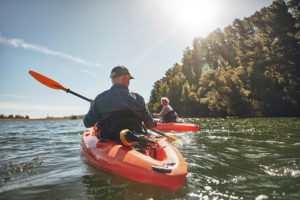 older couple in single kayaks in lake