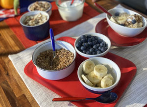red white and blue colored bowls and flatware with oats, blueberries and sliced bananas