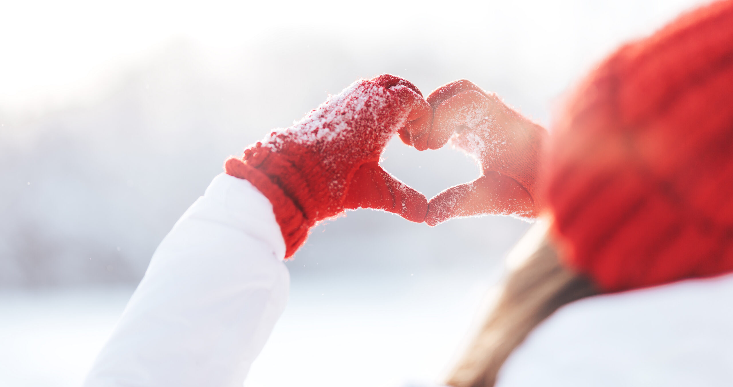 woman making a heart with her hands during winter